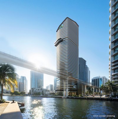 City skyline with tall modern buildings along a river, with the sun shining and a bridge overhead
